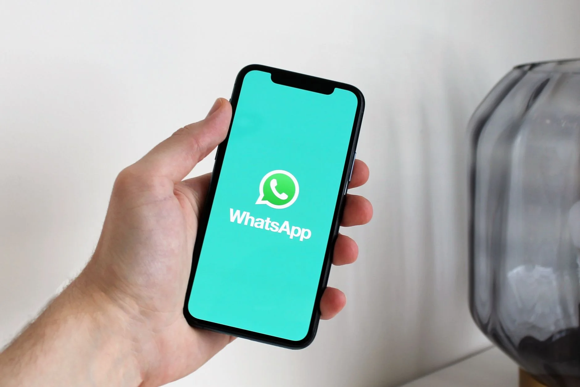 Hand holding a smartphone displaying the WhatsApp screen