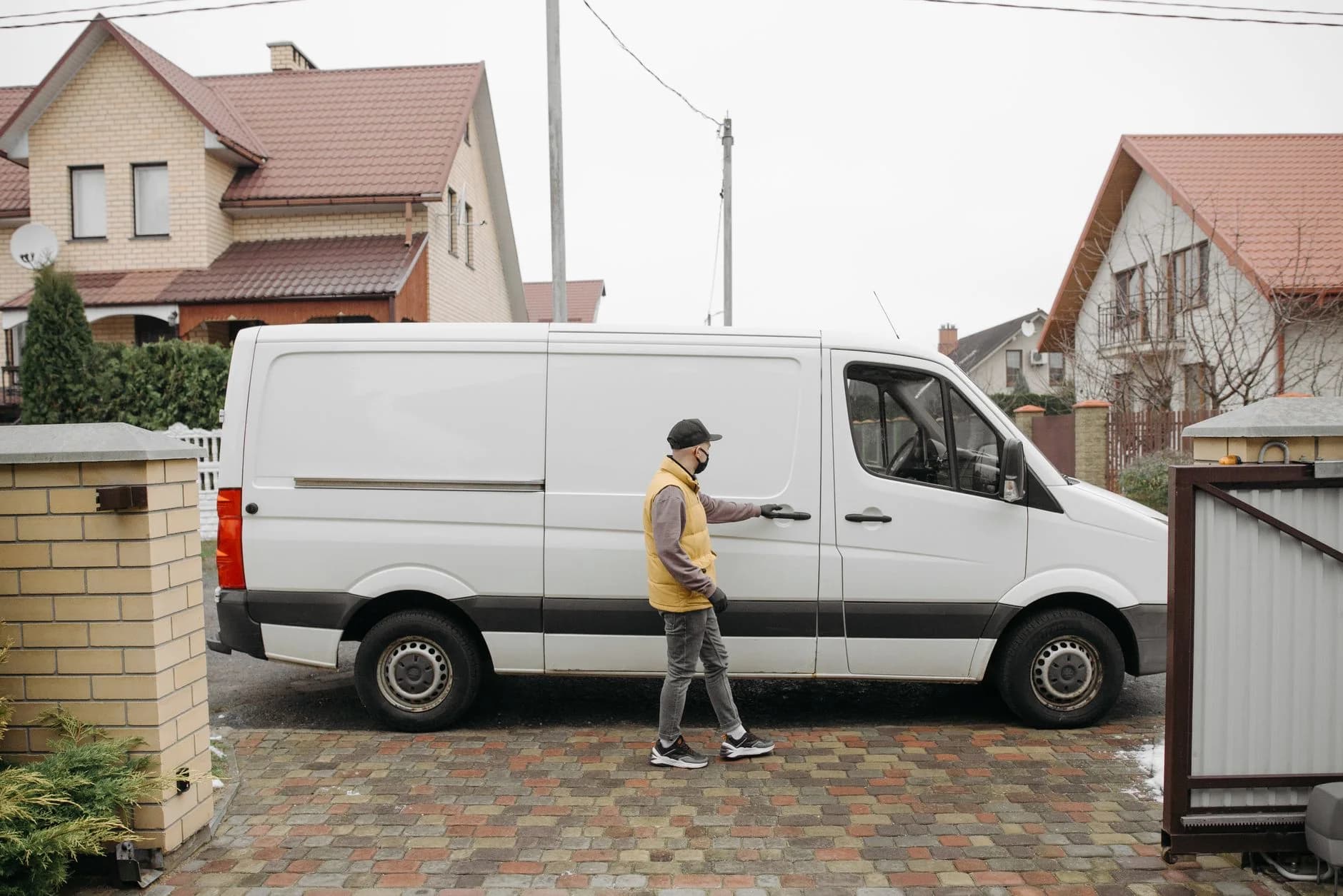 A delivery man exits a white van in a suburban residential neighbourhood